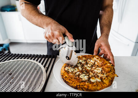 Close up shot of man slicing pizza Banque D'Images