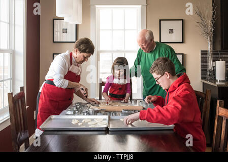 Petits-enfants Aider les grands-parents dans making gingerbread cookies à la maison Banque D'Images