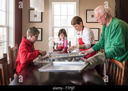 Petits-enfants et grands-parents making gingerbread cookies à la maison Banque D'Images