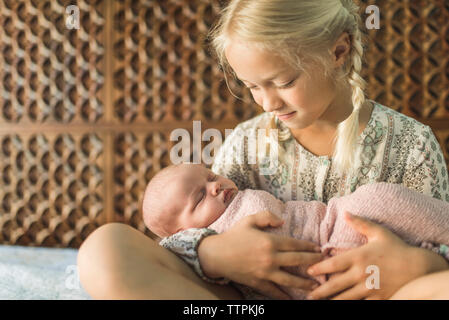 À la soeur de bébé nouveau-né tout en portant son on bed Banque D'Images