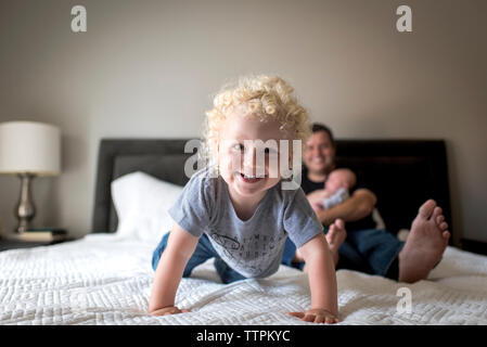 Portrait of smiling boy with père exerçant son frère sur le lit chez lui Banque D'Images