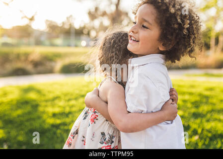 Vue latérale du parc de frères et sœurs heureux Banque D'Images