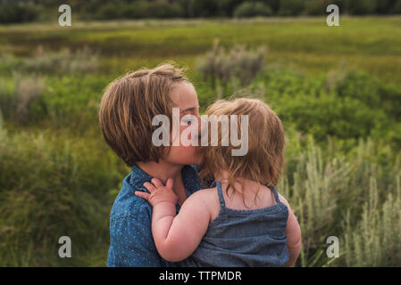 Vue latérale d'exécution fille sœur en se tenant sur le terrain herbeux en forêt Banque D'Images
