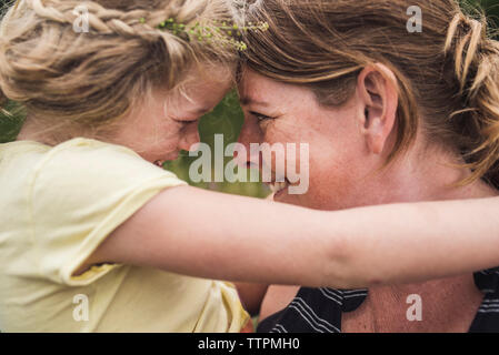 Close-up of happy mother carrying daughter while standing in forest Banque D'Images