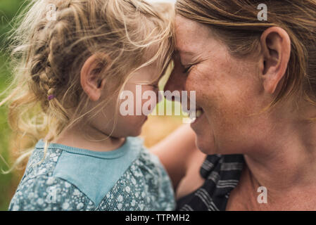 Close-up of happy mother carrying mignon fille debout dans la forêt Banque D'Images