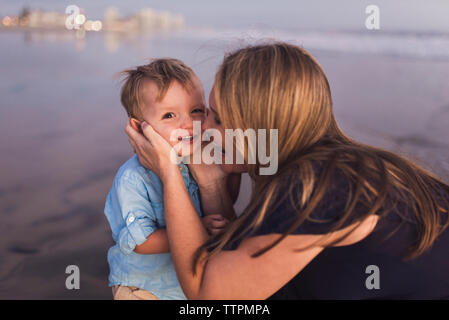 Heureux mère jouissant avec fils à la plage pendant le coucher du soleil Banque D'Images