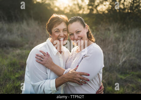 Portrait de Mère et fille adultes embracing and smiling at camera Banque D'Images