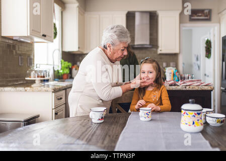 Petite-fille et grand-mère à la table de cuisine Banque D'Images