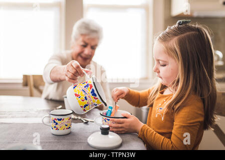 Petite-fille et grand-mère dans la cuisine à jouer avec un service à thé Banque D'Images