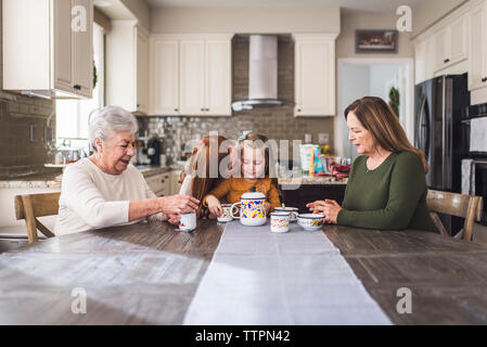 Famille de plusieurs générations de jouer avec un plateau de table de cuisine Banque D'Images