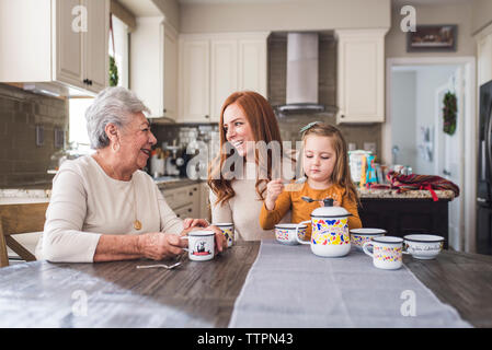 Famille de plusieurs générations de jouer avec un plateau de table de cuisine Banque D'Images