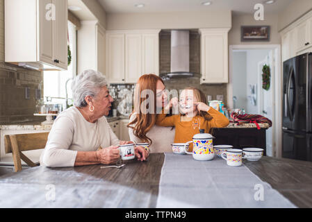 Famille de plusieurs générations de jouer avec un plateau de table de cuisine Banque D'Images