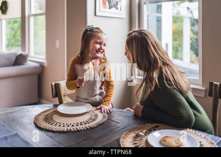 Petite-fille de manger des crêpes tout en souriant à grand-mère Banque D'Images