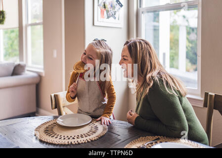 Petite-fille de manger des crêpes pendant que grand-mère regarde sur Banque D'Images