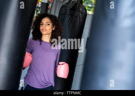 Portrait de boxer rose portant des gants de boxe alors qu'il se trouvait dans une salle de sport sac de frappe par Banque D'Images