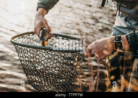 Portrait male hiker tenant un poisson tout en se tenant dans river Banque D'Images