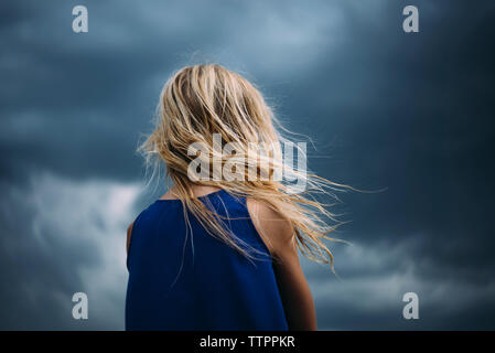 Low angle view of Girl standing against cloudy sky Banque D'Images