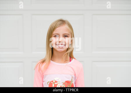 Portrait of smiling Girl standing against door Banque D'Images