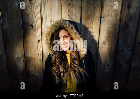 Portrait de femme au manteau d'hiver assis contre la clôture en bois Banque D'Images