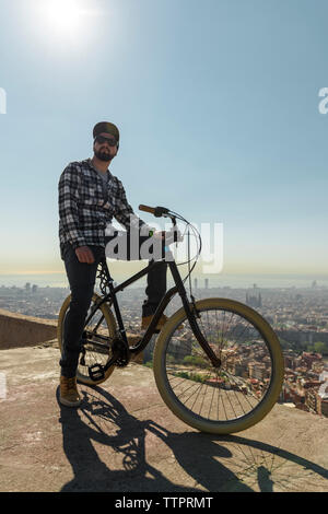 Vue de côté de l'homme assis avec location d'un mur de soutènement sur of contre ciel bleu clair au cours de journée ensoleillée Banque D'Images