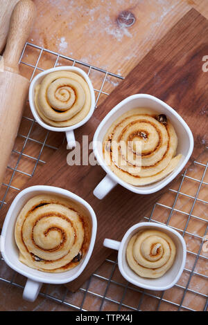 Close-up de brioches à la cannelle dans cups sur grille métallique à compteur de cuisine Banque D'Images