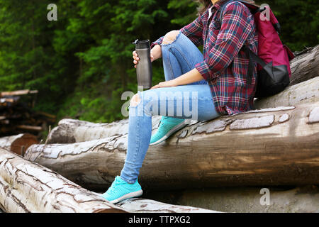 Femme assise sur le tas de bois rond près de la forêt Banque D'Images