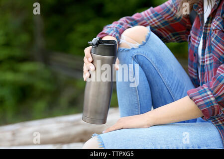 Femme assise sur le tas de bois rond près de la forêt Banque D'Images