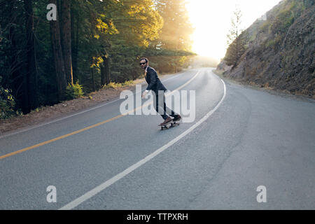 homme d'affaires skateboard dans la rue le jour ensoleillé Banque D'Images