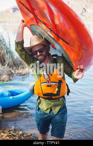 Portrait of happy man carrying paddleboard au Lakeshore Banque D'Images