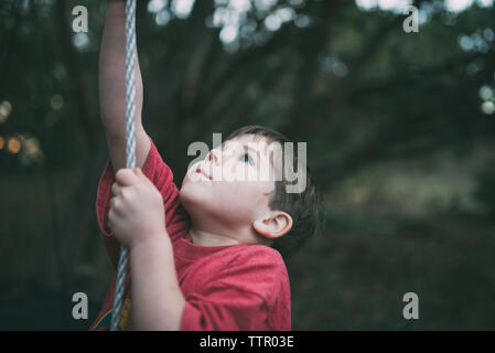 Cute boy jusqu'à la corde d'escalade à l'aire de jeux tandis que Banque D'Images