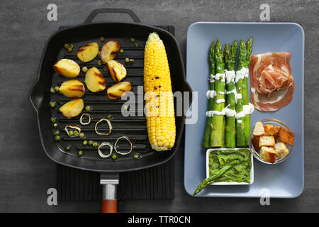 Les asperges avec la sauce dans une assiette et les légumes grillés sur pan Banque D'Images