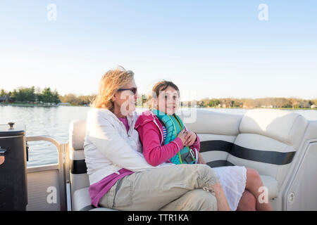 Heureux grand-mère avec sa petite-fille assis en bateau sur le lac contre le ciel clair Banque D'Images