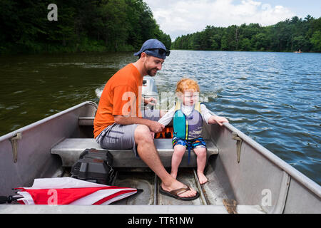 Toute la longueur de père et fils assis en bateau dans le lac de Forest Banque D'Images