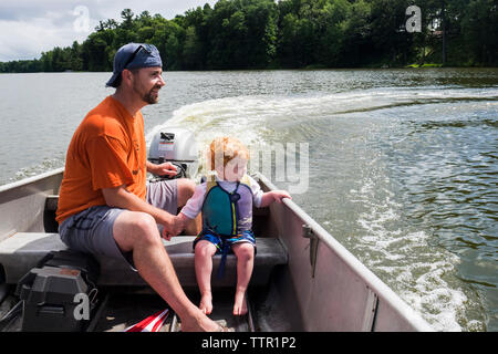 Père et fils dans le lac en bateau à moteur bénéficiant de Forest Banque D'Images