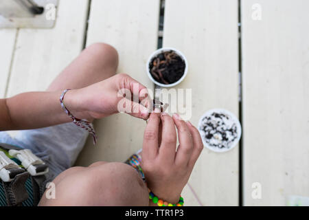 High angle view of girl putting ver en crochet sur pier Banque D'Images