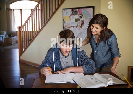 Smiling mother looking at fils étudier sur table Banque D'Images