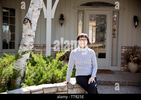 Senior femme assise sur l'extérieur d'un mur de chambre Banque D'Images