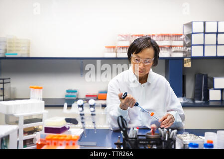 Senior female scientist using pipette in laboratory Banque D'Images