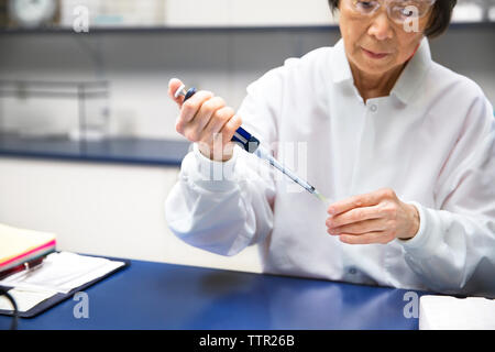 Scientifique senior à la pipette au cours d'expérience en laboratoire Banque D'Images