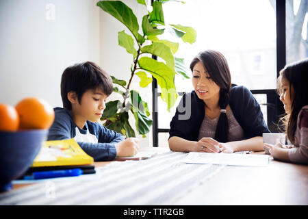 L'enseignement aux enfants de la mère sur la table à la maison Banque D'Images