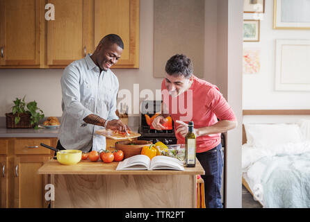 Professionnels multi-ethnic couple gay préparer les repas dans la cuisine à la maison Banque D'Images