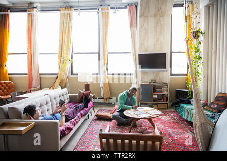 L'homme homosexuel dessin pendant partner using tablet computer in living room Banque D'Images