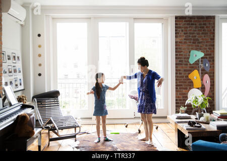 Mère et fille se tenant la main et danser sur un tapis à la maison Banque D'Images