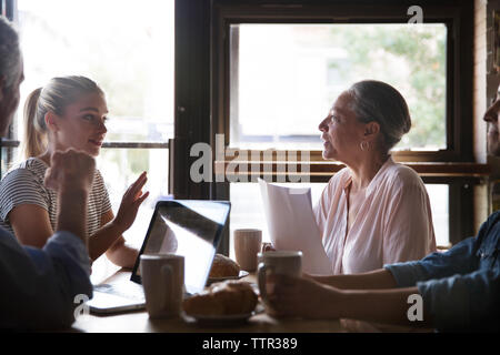 les gens d'affaires parlant tout en prenant un café pendant la réunion au café Banque D'Images