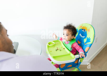 Portrait du père à la fille à s'asseoir sur la chaise haute Banque D'Images