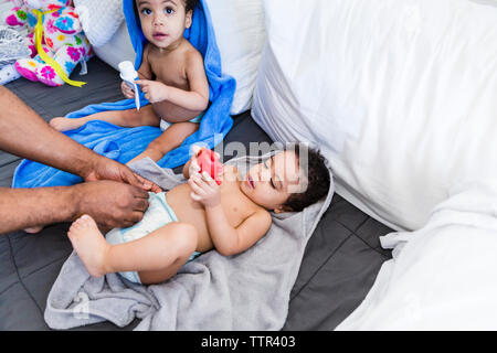 Cropped mains du père de changer la couche de bébé fille avec fille, assis près d'elle Banque D'Images