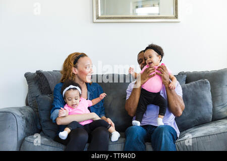 Heureux parents de jouer avec leurs filles alors qu'il était assis sur le canapé Banque D'Images