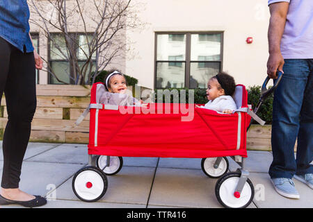 La section basse des parents par les filles debout assis en poussette sur sentier Banque D'Images