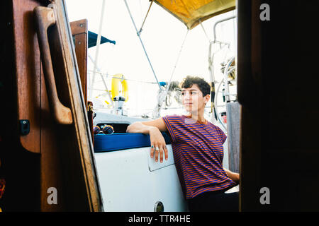 Thoughtful woman looking away while sitting in bateau contre ciel vu par la fenêtre Banque D'Images