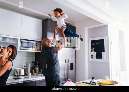 Heureux parents jouer avec les enfants en se tenant debout dans la cuisine à la maison Banque D'Images